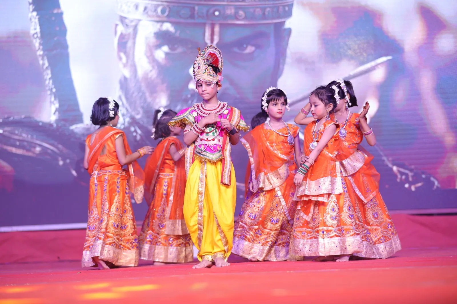 Young students dressed as Krishna and gopis performing on stage