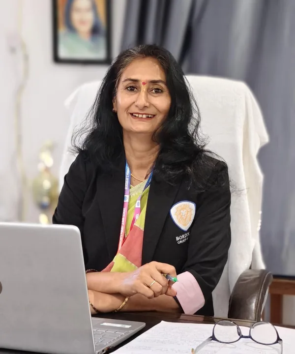 Mrs. Renu Mishra, Principal, smiling at her desk in the school office