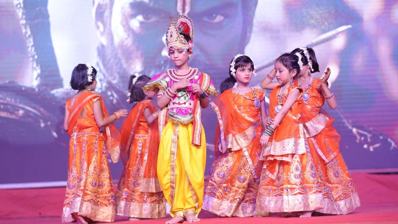 Young students dressed as Krishna and gopis performing on stage